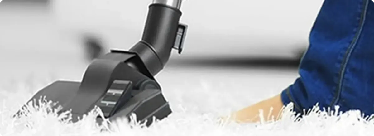 Close-up of a professional vacuuming a white carpet in Fairfax.